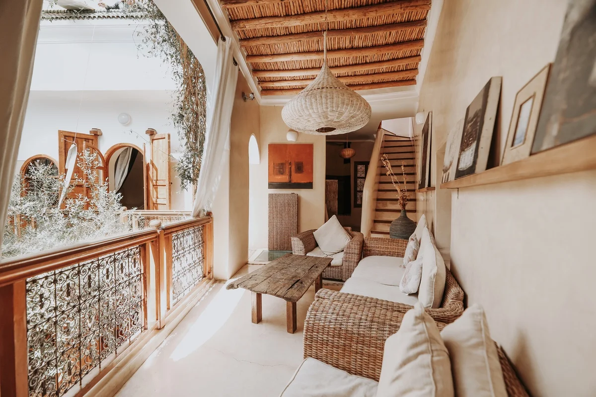 The gallery of Dar Nour el Houda &mdash; the painter's framed canvases resting on their wooden ledge, above the wicker sofas