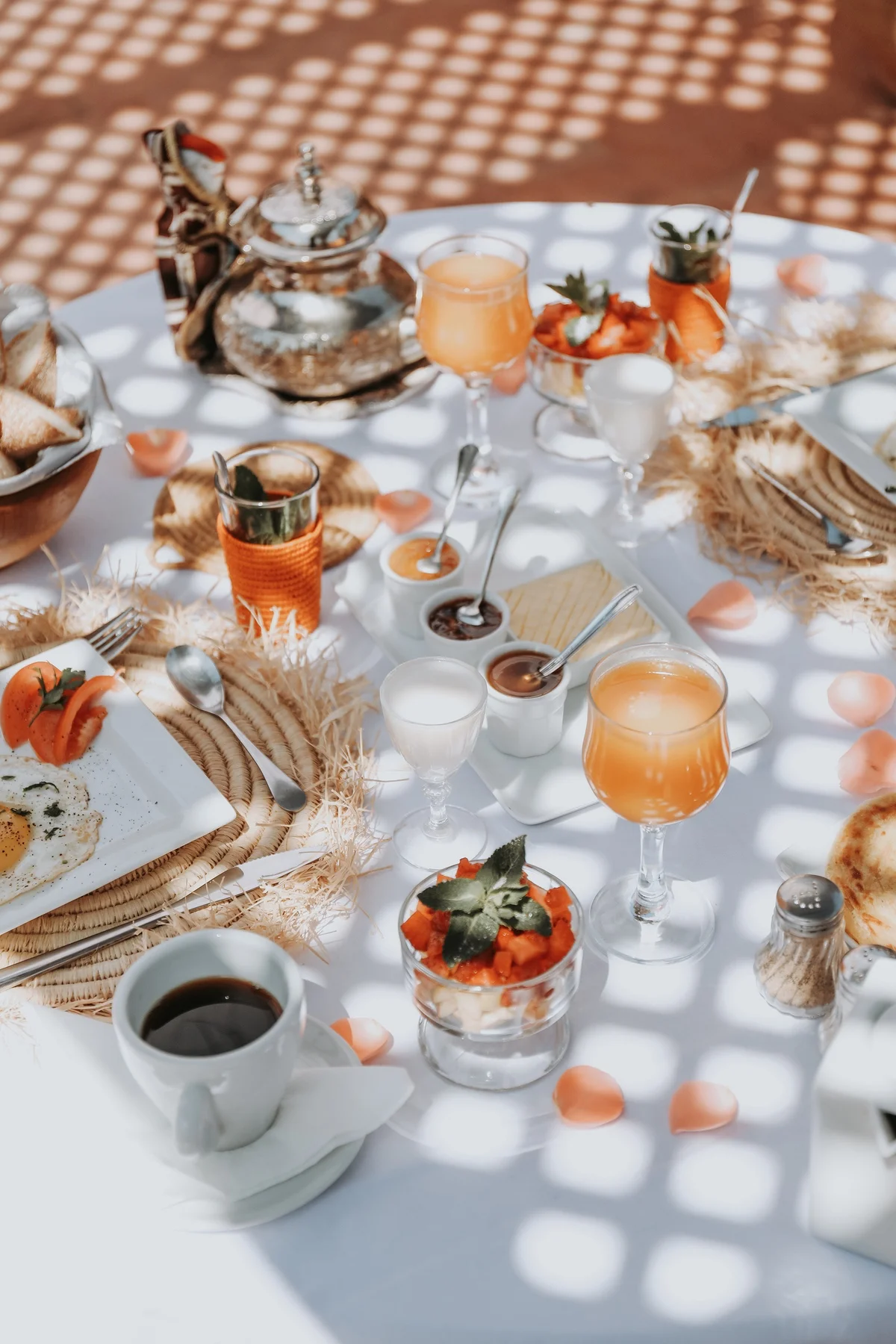 Breakfast served on the terrace &mdash; a brass teapot, fresh orange juice and light sifted through the pergola