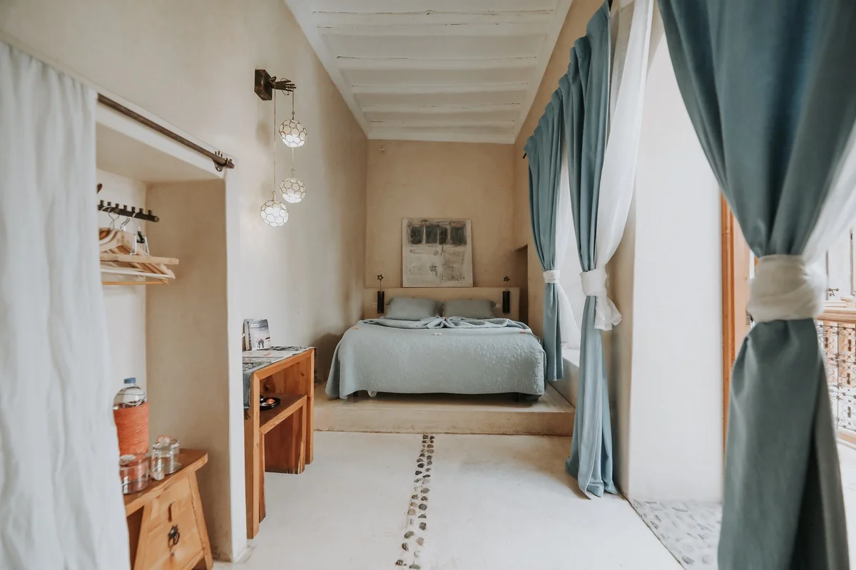 A room in soothing beiges and soft blue, one of the painter's works above the bed