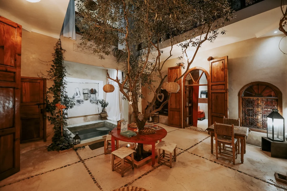 The patio of Dar Nour el Houda at nightfall — the pool, lit lanterns and one of the painter's canvases