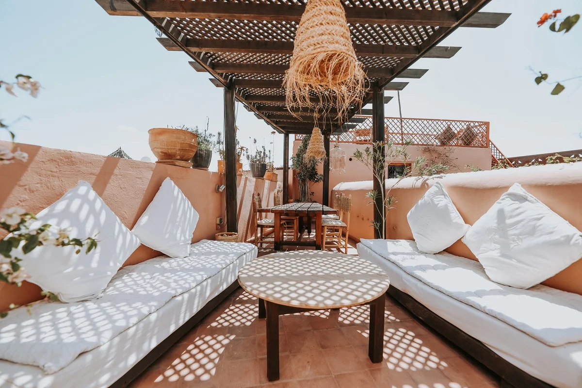 The terrace of Dar Nour el Houda under its pergola — white banquettes in dappled light