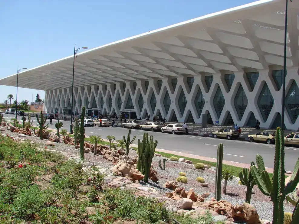 The Marrakech-Menara airport terminal under a blue sky, its white latticework rising behind the cacti